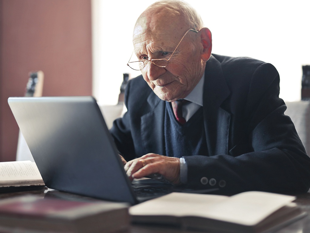 Ein alter Mann sitzt an seien Laptop
